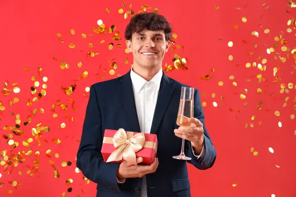 Kırmızı Arka Planda Şampanya Noel Hediyesi Olan Genç Bir Adam — Stok fotoğraf