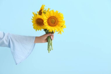 Young woman with beautiful sunflowers on blue background