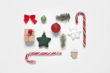 Beyaz arka planda hediye kutusu, baston şekerler ve Noel süslemeleri olan güzel bir kompozisyon.