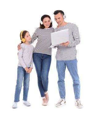 Mutlu aile beyaz arka planda dizüstü bilgisayar ve kulaklık kullanıyor.