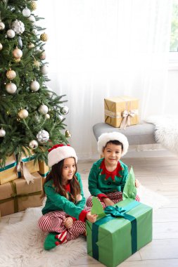 Sevimli küçük çocuklar Noel hediyelerini evde açıyorlar.