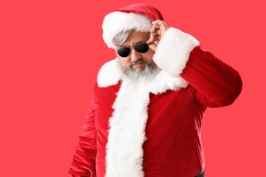 Kırmızı arka planda güneş gözlüklü havalı Noel Baba