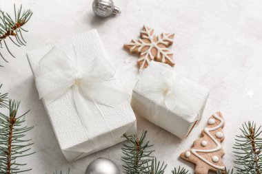 Noel ağacı dalları hediye kutuları ve beyaz arka planda kurabiyeler