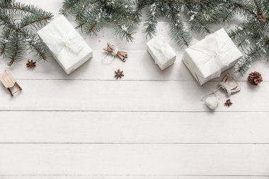 Noel ağacı dalları ve hediye kutuları beyaz ahşap arka planda