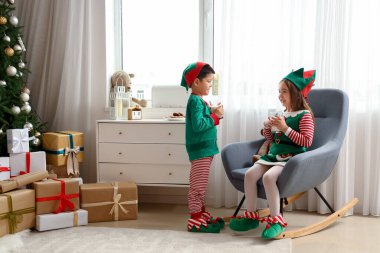 Noel arifesinde evde sütle elf gibi giyinmiş şirin çocuklar.