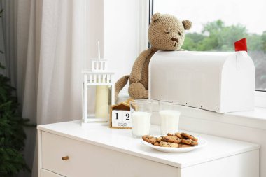 Odadaki çekmecelerin üzerinde süt ve kurabiye olan Noel feneri.