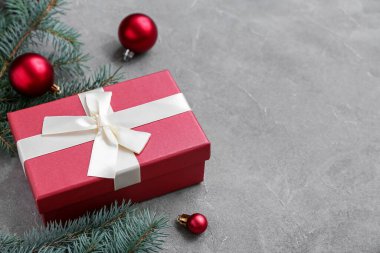 Topları ve gri arka planda hediye kutusu olan Noel ağacı dalları