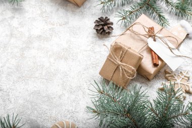 Beyaz zemin üzerinde koni ve hediye kutuları olan Noel ağacı dalları