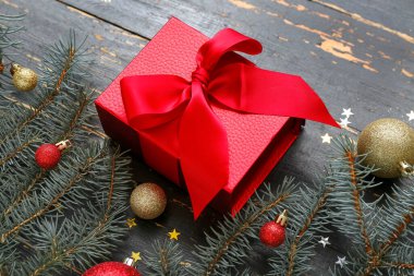 Topları olan Noel ağacı dalları ve siyah ahşap arka planda hediye kutusu