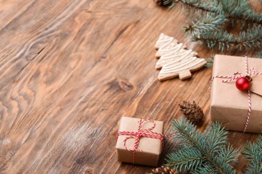 Noel ağacı dalları hediye kutuları ve ahşap arka planda kurabiyeler