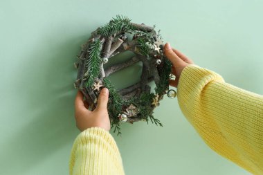 Yeşil duvarı Noel çelengiyle süsleyen kadın, yakın plan.