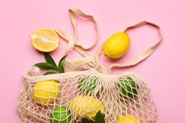 Pembe arka planda limon ve limon dolu bir torba.