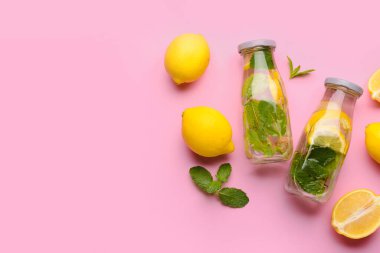 Pembe arka planda naneli lezzetli limonata şişeleri.