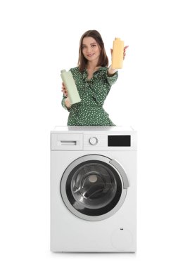 Çamaşır deterjanı ve çamaşır makinesiyle beyaz arka planda genç bir kadın.