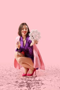Pembe arka planda bir bardak şampanya ve kar tanesi olan genç bir kadın. Yeni yıl kutlaması