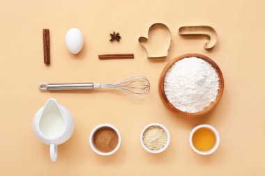 Renkli arka planda Noel kurabiyeleri, çırpıcı ve kesicileri hazırlamak için malzemeler içeren kompozisyon