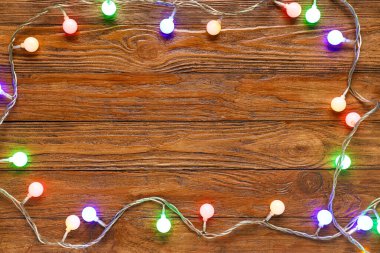 Ahşap arka planda güzel Noel ışıklarından yapılmış çerçeve