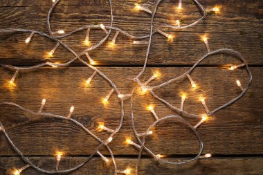 Glowing Christmas lights on wooden background clipart