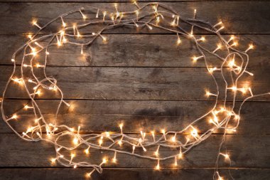 Koyu ahşap arka planda parlayan Noel ışıklarından yapılmış çerçeve