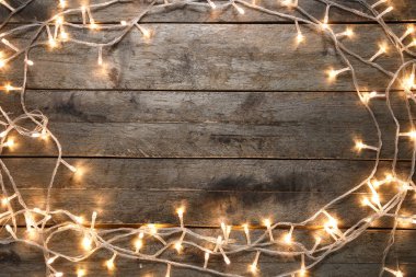 Koyu ahşap arka planda parlayan Noel ışıklarından yapılmış çerçeve