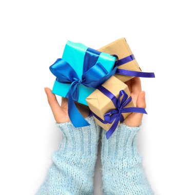 Beyaz arka planda Noel hediyeleriyle dolu kadın elleri, yakın plan.