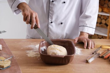 Genç aşçı fırında ekmek pişirmeye hazırlanıyor.