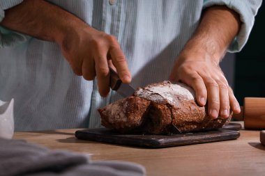 Genç adam fırında taze ekmek kesiyor.