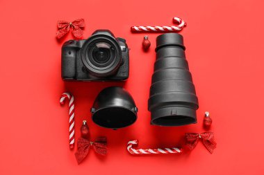 Kırmızı arka planda Noel dekoru olan fotoğrafçı ekipmanları