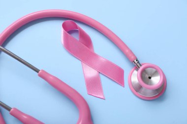 Mavi arka planda steteskoplu pembe kurdele, yakın plan. Göğüs kanseri farkındalığı konsepti