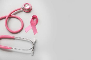 Gri arka planda steteskoplu pembe kurdele. Göğüs kanseri farkındalığı konsepti