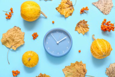 Sonbahar yapraklı çalar saat ve mavi arka planda balkabakları