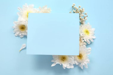Mavi arka planda güzel beyaz kasımpatı çiçekleri olan boş bir kart.