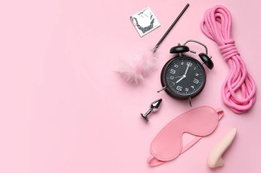 Pembe arka planda seks oyuncakları ve prezervatifli çalar saat.