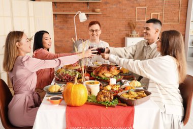 Bir grup genç arkadaş Şükran Günü 'nde şenlik masasında yemek yiyor.