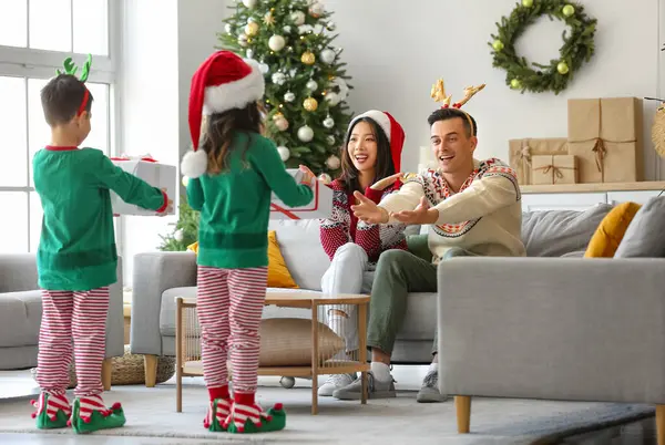 Šťastní Rodiče Dostávají Vánoční Dárky Svých Malých Dětí Doma — Stock fotografie