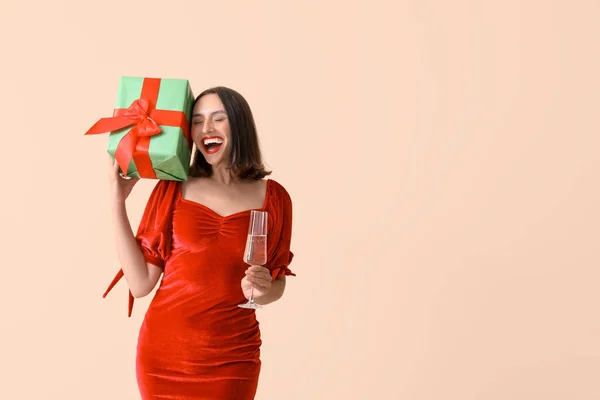 Прекрасная Счастливая Молодая Женщина Бокалом Шампанского Рождественской Подарочной Коробкой Бежевом — стоковое фото