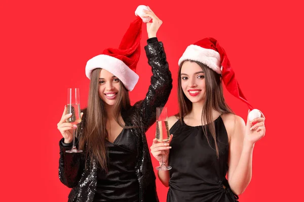 Όμορφες Χαρούμενες Νεαρές Γυναίκες Σάντα Καπέλα Ποτήρια Σαμπάνιας Κόκκινο Φόντο — Φωτογραφία Αρχείου