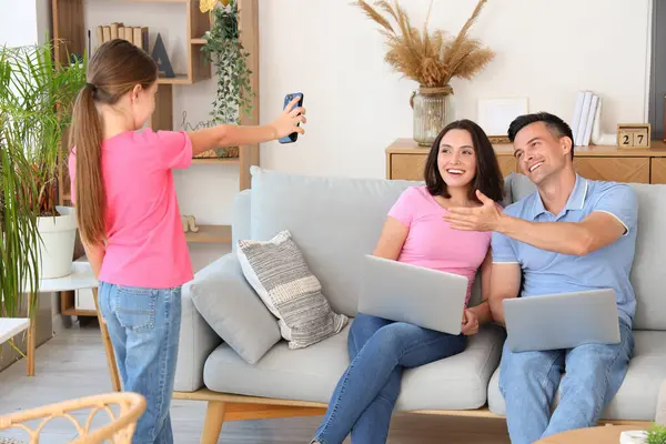 Happy family with laptop and mobile phone resting in living room