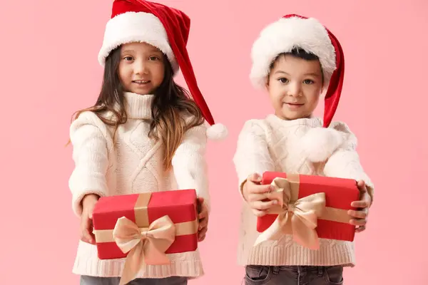 Niedliche Kleine Kinder Mit Weihnachtsgeschenken Auf Rosa Hintergrund — Stockfoto