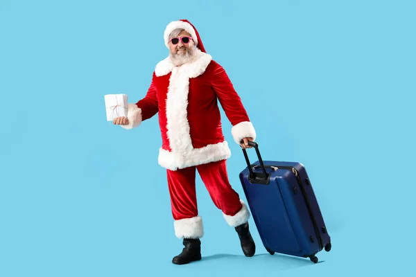 Santa Claus with suitcase and letters on blue background