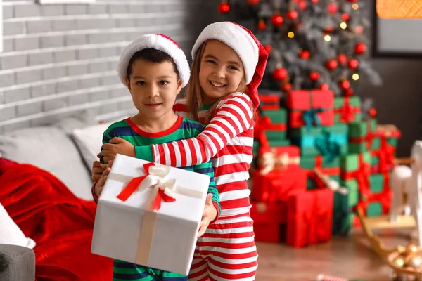 Noel Baba şapkalı şirin çocuklar Noel arifesinde evde birbirlerine sarılıyorlar.