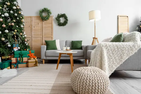 Noel ağacı ve gri kanepeli şenlikli oturma odasının içi.