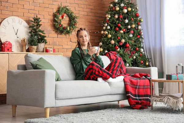 Noel arifesinde evde oturan bir fincan kakaolu genç kadın.