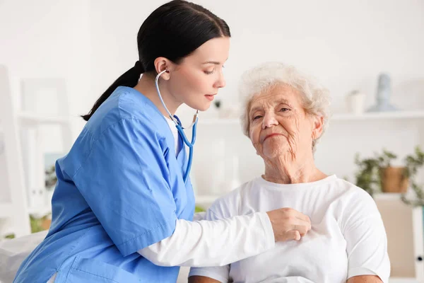 Женщина Медсестра Слышит Пожилую Женщину Стетоскопом Спальне — стоковое фото