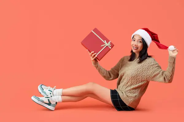 戴着圣诞礼帽 头戴红色背景礼品盒的年轻美丽的亚洲女人 — 图库照片