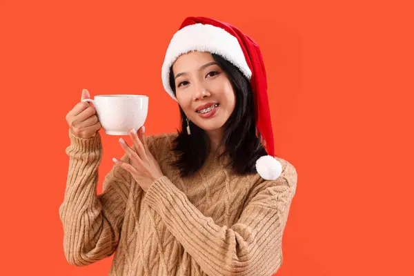 Молодая Красивая Азиатка Санта Шляпе Чашкой Чая Красном Фоне — стоковое фото