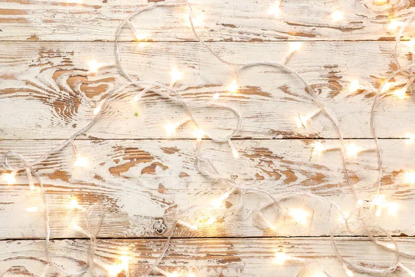 Beyaz ahşap arka planda parlayan Noel ışıkları
