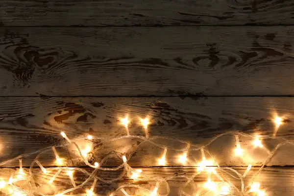 Koyu ahşap arka planda parlayan Noel ışıkları