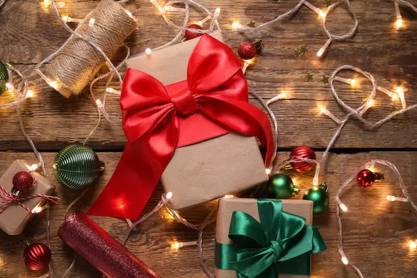 Weihnachtsgeschenke Mit Kugeln Seil Geschenkpapier Und Leuchtenden Lichtern Auf Holzgrund — Stockfoto