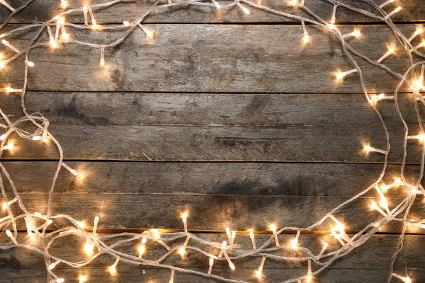 Koyu ahşap arka planda parlayan Noel ışıklarından yapılmış çerçeve